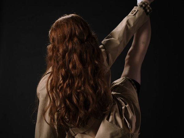 Person performing fluid stretching movements in a dark studio.